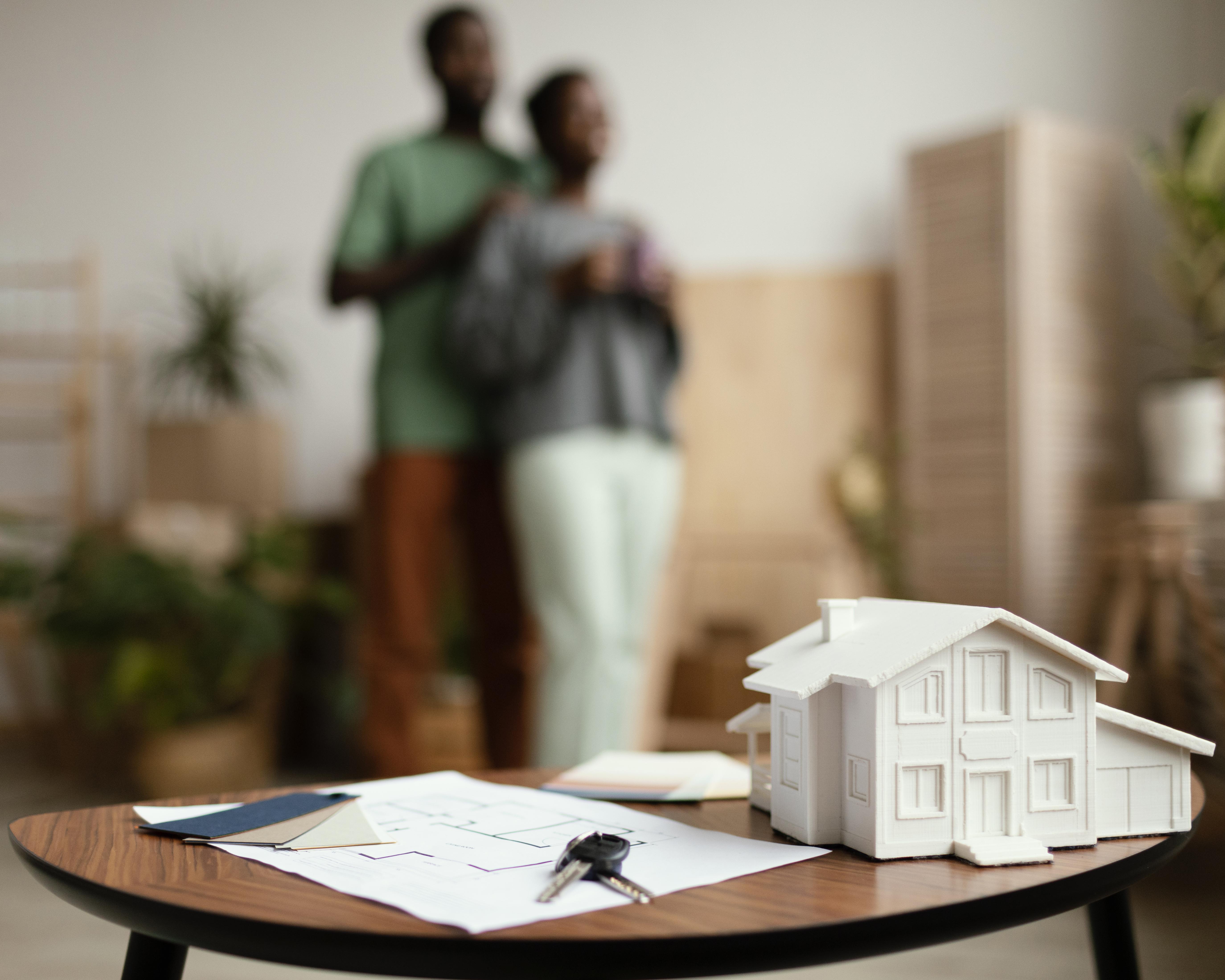 Home nouvelles cles de la maison et plan sur table avec couple defocalise